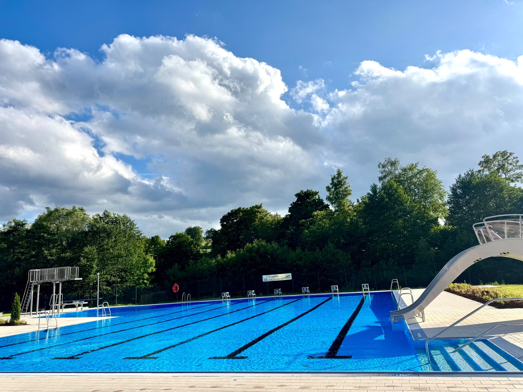 Schwimmbahnen im Freibad Rengshausen unter blauem Himmel mit Wolken