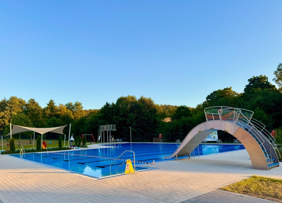 Freibad Rengshausen bei Sonnenschein mit großer Wasserrutsche und Sonnensegel