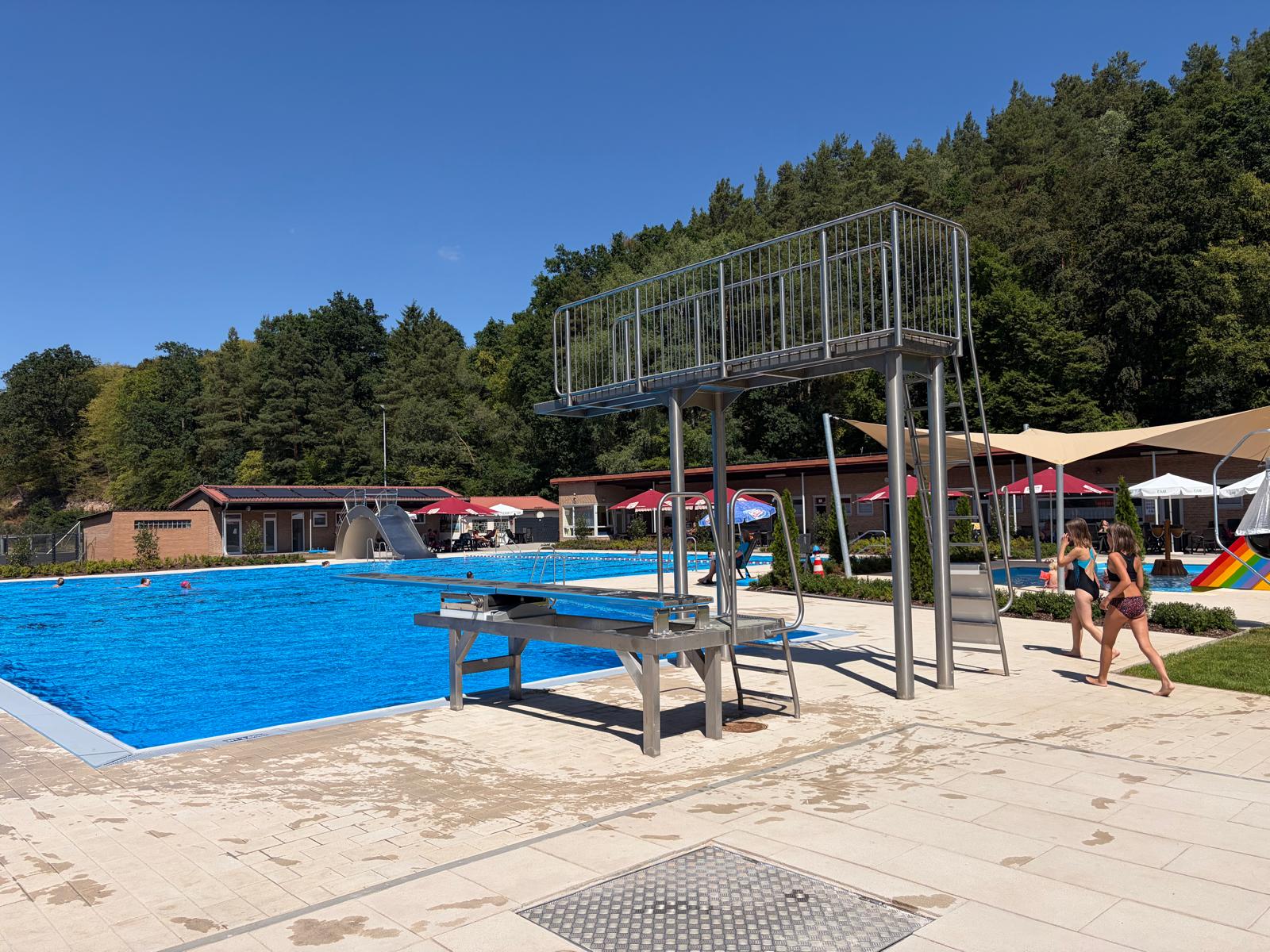 Beheiztes Freibad mit großem Becken, Sprungturm und Liegewiese im Sommer