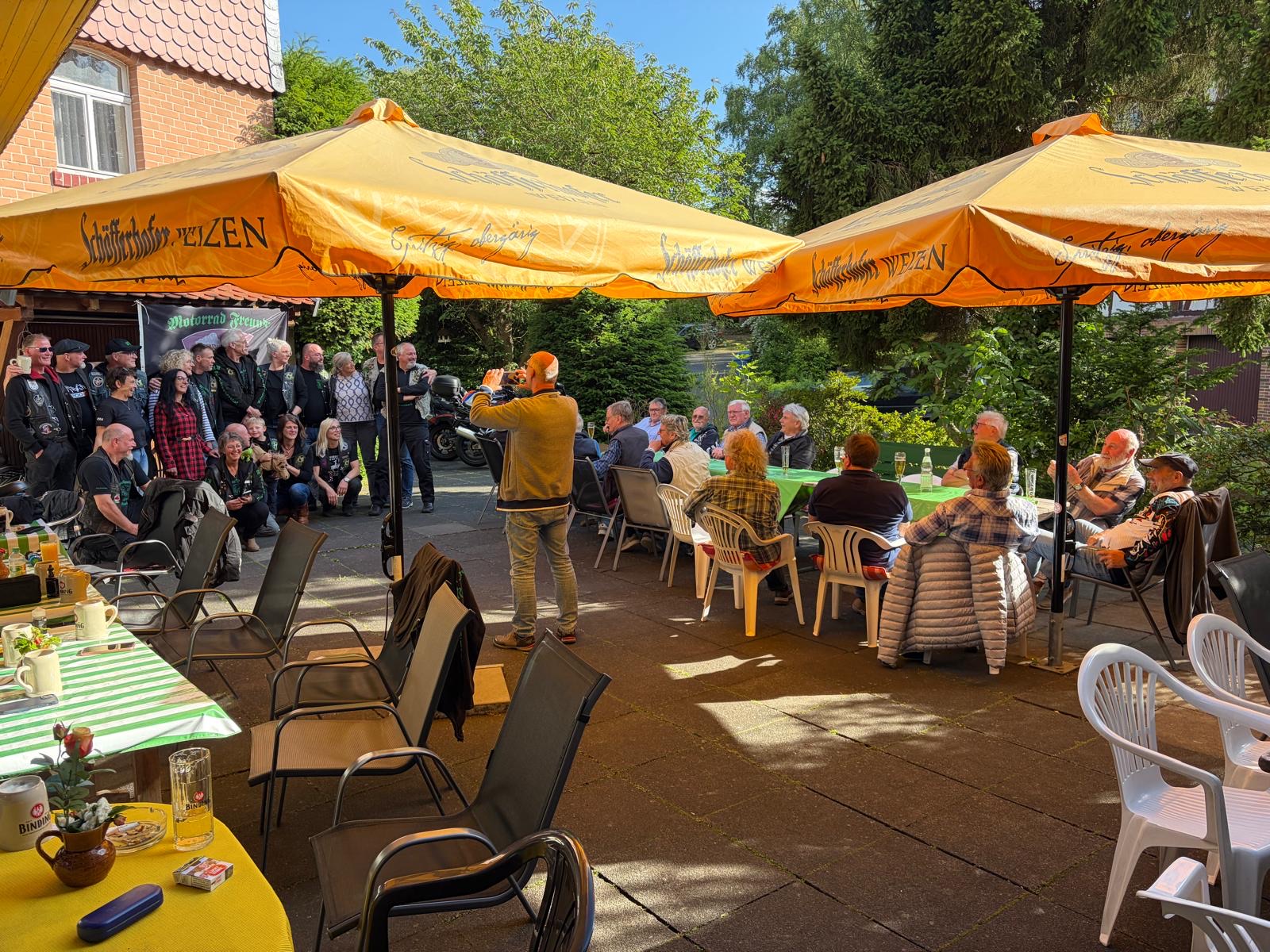 Volle Hofterrasse beim Bikertreffen unter Sonnenschirmen